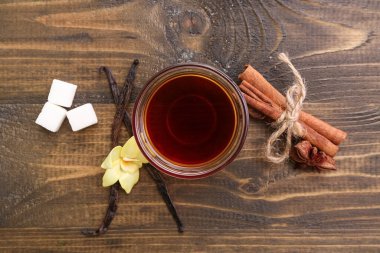 İçinde vanilya özü ve ahşap arka planda baharatlar olan kompozisyon.