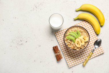 Lezzetli yulaf ezmesi, muz, kivi ve arka planda bir bardak süt.