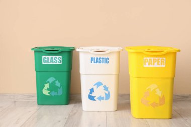 Bej duvarın yakınındaki farklı çöp kutuları için boş çöp kutuları. Geri dönüşüm kavramı