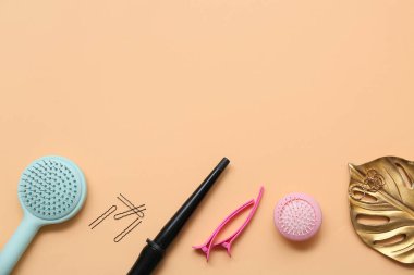 Saç fırçaları ve saç maşaları turuncu arka planda.