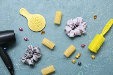 Mavi grunge arka planında saç fırçalı, bigudili ve ipek tokalı saç kurutma makinesi.