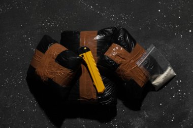 Koyu arkaplan üzerinde bıçak bulunan uyuşturucu paketleri