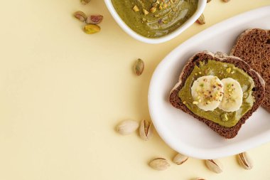 Fıstık ezmeli ekmek parçaları ve sarı arka planda muz dilimleri.