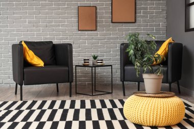 Modern oturma odasının içinde siyah koltuklar, masa ve çerçeveler var.