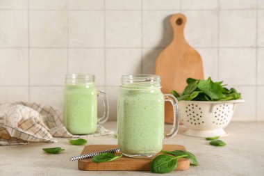 Mason jars of fresh spinach smoothie on white table