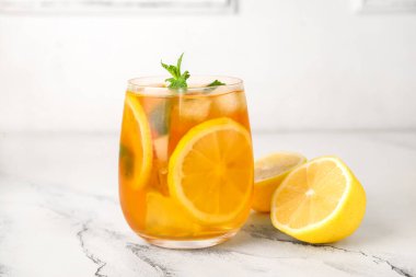 Limonlar ve bir bardak lezzetli soğuk buzlu çay mermer arka planda, yakın plan.