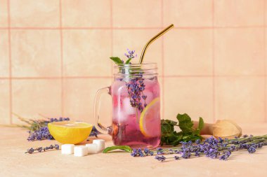 Mason kavanozu taze lavanta limonata, nane ve ahşap sıkacağı bej masa üzerinde.