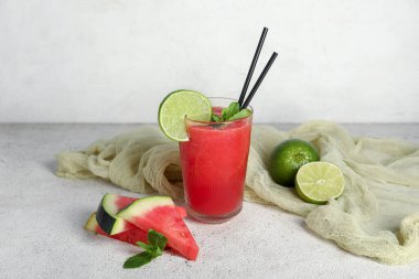 Bir bardak taze karpuz suyu, beyaz arka planda limon ve nane.