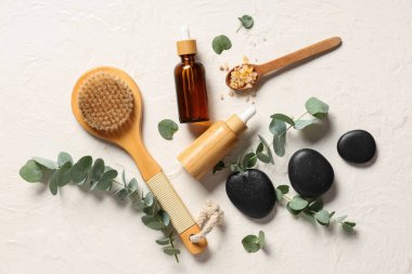 Spa taşları, masaj vücut fırçası ve okaliptüs şişeleri hafif grunge arka planda gerekli yağ