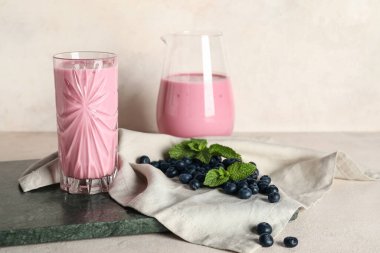 Beyaz arkaplanda nane aromalı bir bardak ve bir sürahi taze yaban mersini.