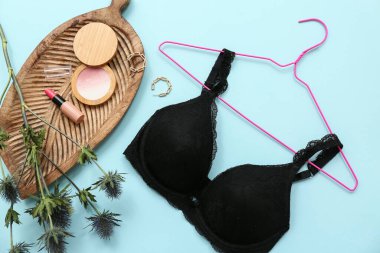 Siyah kadın sütyeni, kozmetik ürünleri ve renk arkaplan üzerine bitki dalı olan kompozisyon
