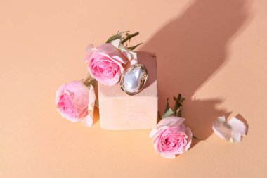 Süslü yüzüklü dekoratif podyum ve bej arka planda güzel güller