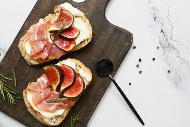 Beyaz arka planda prosciutto ve ricotta peynirli lezzetli incirli bruschetta tahtası.