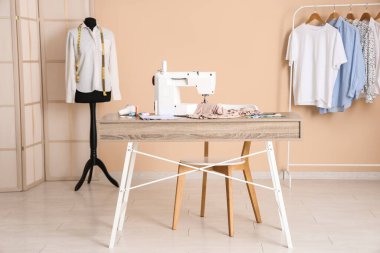 Terzinin dikiş makinesi, farklı malzemeler ve atölye mankeni.