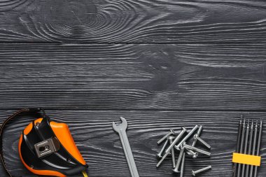 Musluk cıvataları, tornavida parçaları ve siyah ahşap arka plandaki araçlar