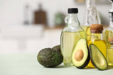 Mutfaktaki yeşil masada taze avokado yağı şişeleri.