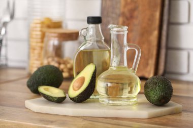 Beyaz tuğla duvarın yanındaki ahşap masada bir şişe taze avokado yağı.