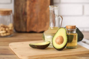 Beyaz tuğla duvarın yanındaki ahşap masada bir şişe taze avokado yağı.