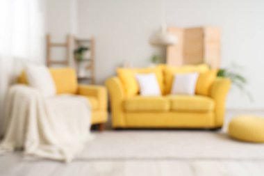 Şık bir oturma odası, rahat sarı koltuğu, kanepesi ve puf.