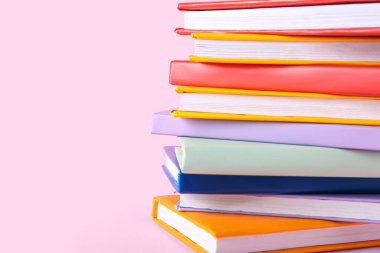 Pembe arkaplan üzerine renkli kitap yığını, yakın plan