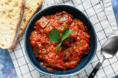 Bir kase sebze yahnisi mavi grunge arka planda dilimlenmiş ekmekle servis edilir.