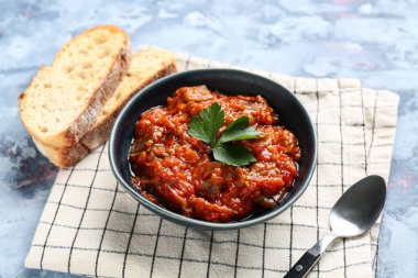 Bir kase sebze yahnisi mavi grunge arka planda dilimlenmiş ekmekle servis edilir.