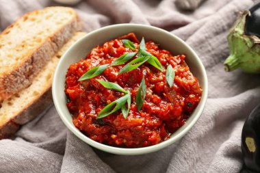 Ekmek dilimleri ve yeşil soğanla servis edilen bir kase sebze yahnisi.