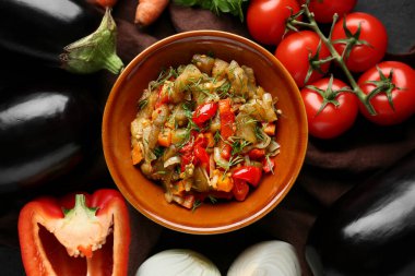 Bowl of vegetable stew with tomatoes, eggplant, carrots and herbs on brown napkin
