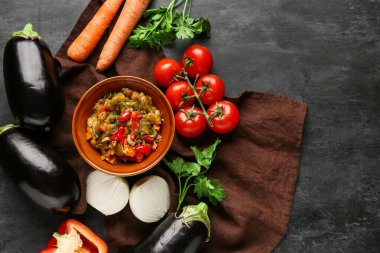 Bowl of vegetable stew with tomatoes, eggplant, carrots and herbs on black background