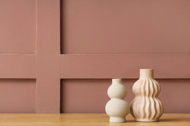 Kahverengi duvara karşı ahşap masadaki farklı vazolar.