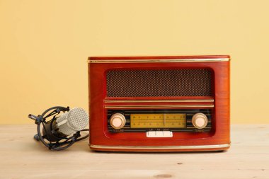 Sarı duvara karşı açık ahşap masada mikrofonu olan klasik radyo alıcısı.