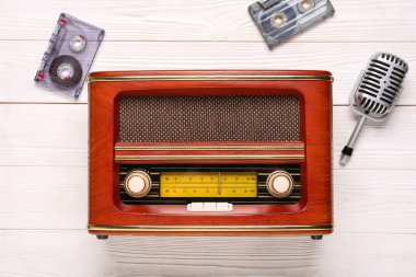 Beyaz ahşap arka planda mikrofon ve ses kasetleri olan klasik radyo alıcısı