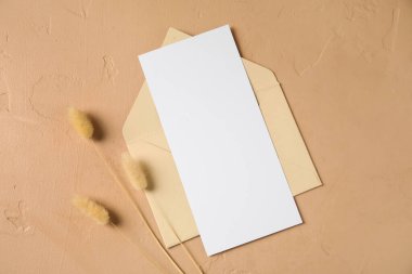 Boş kartla zarf ve bej arka planda kurutulmuş lagurus