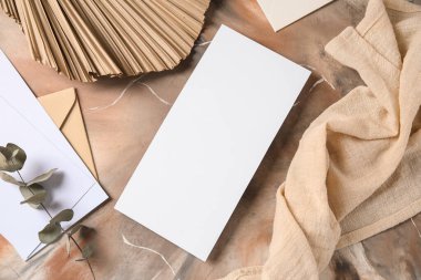 Boş kartlı zarf, okaliptüs dalı, kurumuş palmiye yaprağı ve grunge arka planda kumaş.