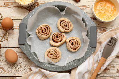 Pişmemiş tarçınlı yemek tabağı ve ahşap arka planda malzemeler.