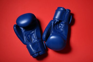 Kırmızı arka planda mavi boks eldivenleri.
