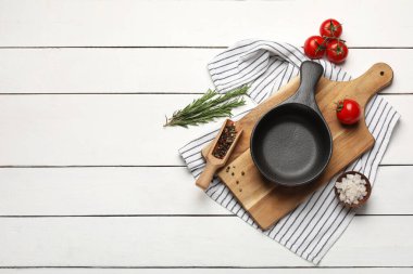 Domatesli kızartma tavası, biberiye, karabiber ve beyaz ahşap arka planda deniz tuzu.