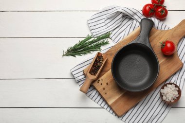 Domatesli kızartma tavası, biberiye, karabiber ve beyaz ahşap arka planda deniz tuzu.