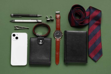 Yeşil arka planda cep telefonu olan farklı erkek aksesuarları.
