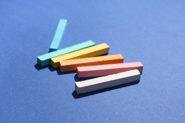 Mavi arkaplanda renkli tebeşir parçaları, yakın plan