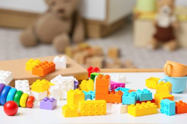 Çocuk odasındaki beyaz masanın üzerinde renkli plastik yapı taşları