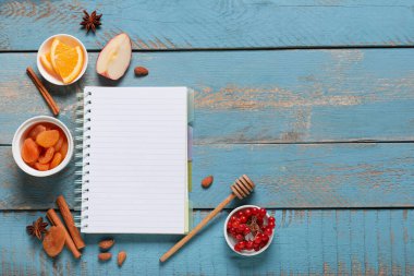 Boş tarif kitabı ve mavi ahşap arka planda pişirme ürünleri içeren kompozisyon