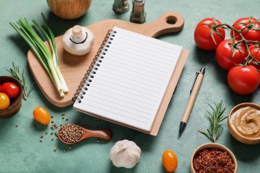 Boş tarif kitabıyla kompozisyon, baharatlar ve yeşil grunge arka planda taze sebzeler, yakın plan