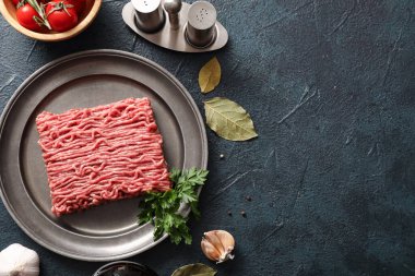 Yeşil grunge arka planda taze et, maydanoz, sarımsak ve defne yapraklı tabak.