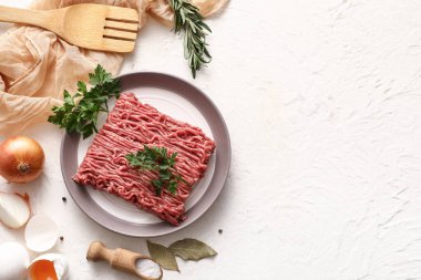 Beyaz arka planda taze et, soğan, maydanoz, defne yaprağı ve yumurta tabağı.