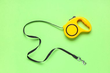 Yeşil arka planda kurşun taşıyan sarı geri çekilebilir köpek tasması