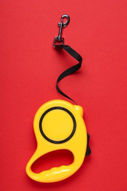 Kırmızı zemin üzerinde kurşun olan sarı geri çekilebilir köpek tasması