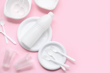 Pembe arka planda plastik sofra takımı ve çatal bıçaklı kompozisyon