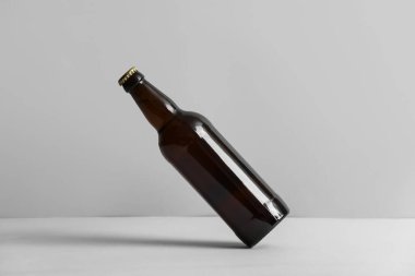 Gri arka planda bir şişe soğuk bira.