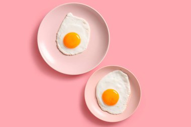 Pembe arka planda lezzetli kızarmış yumurta tabakları.